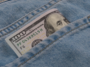 a hundred dollar bill sticking out of the back pocket of a pair of jeans