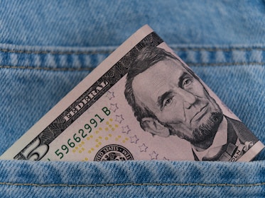 a dollar bill sticking out of the back pocket of a pair of jeans