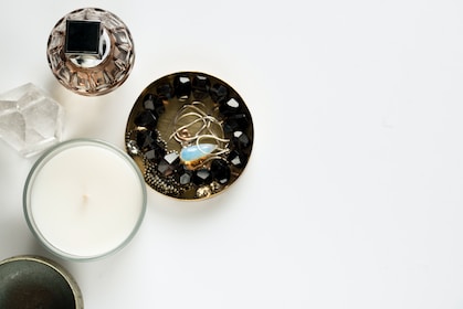 four assorted container and candle on white surface